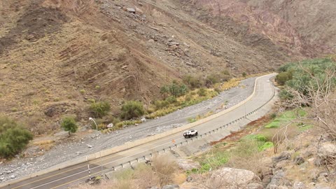 Walking between the rocky mountains using a car as a means of transport, drone footage of Wadi Bani Auf in the Kingdom of Saudi Arabia, the beauty of nature in the Kingdom, rocky mountain ranges, stunning landscapes, tourism in Saudi Arabia, the beauty of the city of Tabuk, the mountainous highlands in Tabuk.