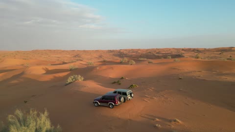 A four-wheel drive vehicle driving on golden sands, recreational activities for driving cars in the Saudi desert, safari adventures on hills and sand dunes, the terrain and dry environment, a tourist destination for adventure lovers, a trip and a wild camping experience in the desert areas of the Great Nafud north of Hail city.
