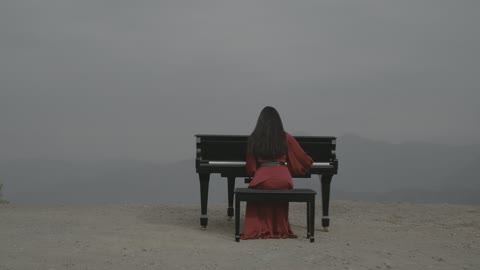 Musical artistic talents, the mountains of Al-Baha in the southern nature of the Kingdom of Saudi Arabia, aerial drone photography of an artist sitting in front of a musical piano and enjoying playing, famous tourist attractions in Riyadh, the peaks and mountain heights.