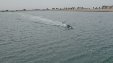 Fun family and youth recreational activities and events, aerial drone photography of water games and sea jet skiing, the Dubai Eye Ferris Wheel on Blue Waters Island during the day, a view of the Arabian Gulf coast in the United Arab Emirates, a famous tourist landmark at Jumeirah Beach in the Emirate of Dubai.