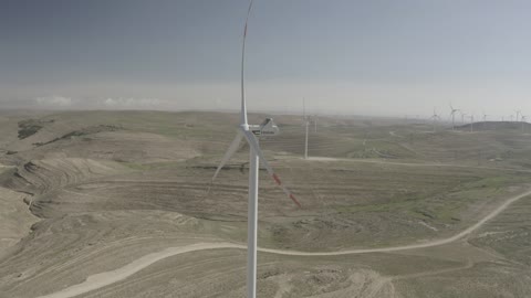 Electricity generation through wind farms, harsh and dry climate, the concept of using renewable energy that is environmentally friendly, sustainable development with alternative energy in Dumat al-Jandal in the Kingdom of Saudi Arabia, aerial drone photography of wind turbine fields and windmills amidst the golden sands in desert areas.