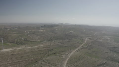 تصوير درون جوي لحقول توربينات الرياح وطواحين الهواء وسط الرمال الذهبية في المناطق الصحرواية، توليد الكهرباء بواسطة مزارع الرياح، مناخ قاسٍ وجاف، مفهوم استخدام الطاقات المتجددة صديقة البيئة، التنمية المستدامة بالطاقة البديلة في دومه الجندل بالمملكة العربية السعودية