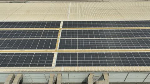 تصوير درون جوي لمجموعة من ألواح الطاقة الكهروضوئية، مفهوم انتاج الطاقة البديلة الصديقة للبيئة في المملكة العربية السعودية, انعكاس اشعة الشمس على محطات الطاقات الشمسية المتجددة