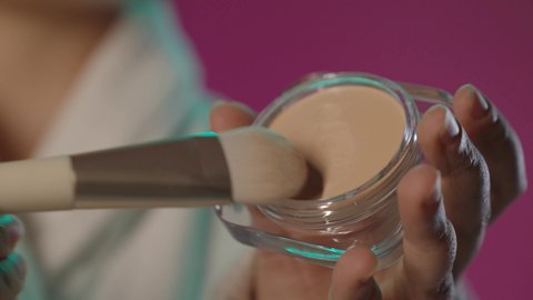 أدوات مكياج تتوريال، الاهتمام بالجمال والمظهر الخارجي، مستحضر تجميلي نسائي, مفهوم التزين و التجمل, بورتريه مقرب ليد مرأة عربية خليجية سعودية تمسك الفرشاة و كريم الأساس