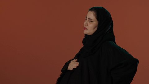 تحمل الم الظهر خلال الحمل و الانجاب، الاهتمام بصحة الجنين، الحفاظ على صحة الأم و الطفل، الأمومة و بداية حياة جديدة، بورتريه لإمرأة عربية خليجية سعودية محجبة ترتدي عباءة سوداء تضع يدها على بطنها بايماءات التألم, خلفية بني