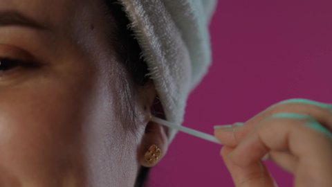 العناية بصحة الأذن، استخدام أعواد و نكاشات القطن، الاعتناء بالنفس و النظافة, بورتريه لامرأة عربيه خليجية سعودية تستخدم نكاشة قطنية, الاهتمام بالمظهر الخارجي, خلفية  بنفسجية