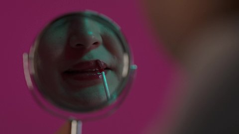 الأنوثة و الاهتمام بالجمال و البشرة و المظهر الخارجي, الشغف بوضع المكياج, بورترية لمرأة عربية خليجية سعودية تنظر في المرآة تحمل أحمر الشفاه، سيدة خبيرة بمستحضرات التجميل، مفهوم التزين و التجمل, خلفية بنفسجية