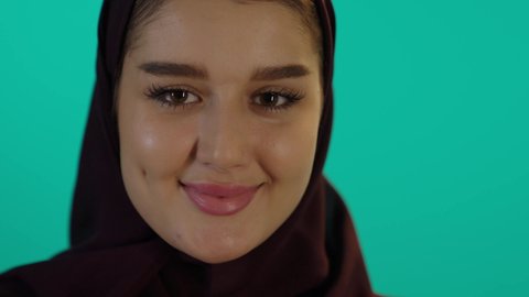 حمل صورة سونار لجنين باللون الابيض والاسود ومشاعر الامومة، مفهوم الحمل والانجاب، الاهتمام بصحة الجنين، الحفاظ على صحتها و صحة طفلها، الاستفادة من العروض الموسمية والتخفيضات، تصوير مقرب لإمراة عربية خليجة سعودية ترتدي العباءة والحجاب  بتعابير السرور، خلفية زرقاء