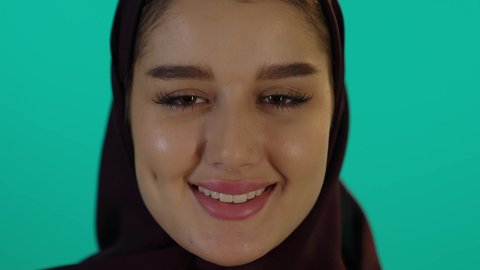 عرض صورة سونار لجنين ومشاعر الامومة، مفهوم الحمل والانجاب، الاهتمام بصحة الجنين، الحفاظ على صحتها و صحة طفلها، الاستفادة من العروض الموسمية والتخفيضات، تصوير مقرب لإمراة عربية خليجة سعودية ترتدي العباءة والحجاب  بتعابير السرور، خلفية زرقاء