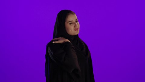 وجع في الكتاف والرقبة خلال الحمل، مفهوم الحمل والانجاب، الاهتمام بصحة الجنين، الحفاظ على صحتها و صحة طفلها،جمال الأمومة وبداية حياة جديدة، تصوير مقرب لإمراة عربية خليجة سعودية ترتدي العباءة والحجاب تنظر إلى الكاميرا بإيماءات التفكير، خلفية بنفسجي