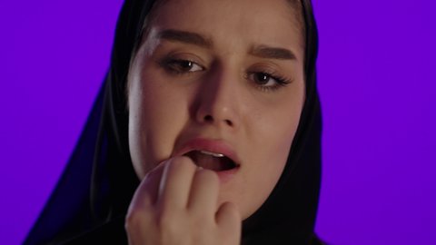 الم الاسنان خلال الحمل، مفهوم الحمل والانجاب، الاهتمام بصحة الجنين، الحفاظ على صحتها و صحة طفلها، جمال الأمومة وبداية حياة جديدة، تصوير مقرب لإمراة عربية خليجة سعودية ترتدي العباءة والحجاب تنظر إلى الكاميرا بإيماءات التفكير، خلفية بنفسجي