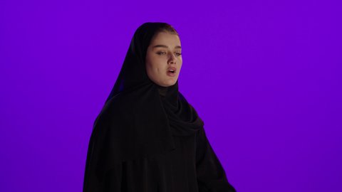 الحاجة للنوم والنعاس خلال الحمل، مفهوم الحمل والانجاب، الاهتمام بصحة الجنين، الحفاظ على صحتها و صحة طفلها، جمال الأمومة وبداية حياة جديدة، تصوير مقرب لإمراة عربية خليجة سعودية ترتدي العباءة والحجاب تنظر إلى الكاميرا بإيماءات التفكير، خلفية بنفسجي