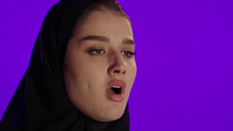 النعاس والتعب خلال الحمل، مفهوم الحمل والانجاب، الاهتمام بصحة الجنين، الحفاظ على صحتها و صحة طفلها، جمال الأمومة وبداية حياة جديدة، تصوير مقرب لإمراة عربية خليجة سعودية ترتدي العباءة والحجاب تنظر إلى الكاميرا بإيماءات التفكير، خلفية بنفسجي