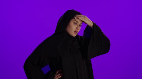 التعب والارهاق وآلام الرأس، مفهوم الحمل والانجاب، الاهتمام بصحة الجنين، الحفاظ على صحتها و صحة طفلها، جمال الأمومة وبداية حياة جديدة، تصوير مقرب لإمراة عربية خليجة سعودية ترتدي العباءة والحجاب تنظر إلى الكاميرا بإيماءات التفكير، خلفية بنفسجي