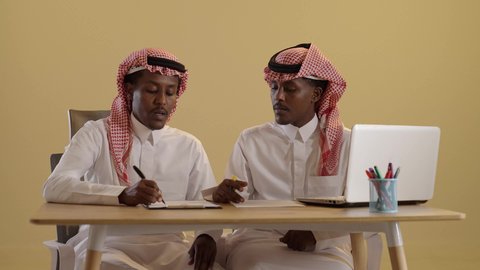 الدراسة عن بعد، بورتريه لطالبان توأم ذو بشرة سمراء عربيان خليجيان سعوديان يرتديان الثوب والشماغ السعودي يستخدمان اللابتوب، تدوين الملاحظات والمعلومات, المشاركة والتعاون، خلفية بنية