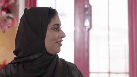 الطعام التقليدي في وقت الفطور اقراص الفلافل، الاستمتاع بالمشروبات الباردة, قضاء أوقات ممتعة في المطعم, مطاعم و كافيهات المملكة العربية السعودية, شابة عربية خليجية سعودية مبتسمة محجبة ترتدي العباءة والحجاب تجلس على الطاولة و تتناول الطعام