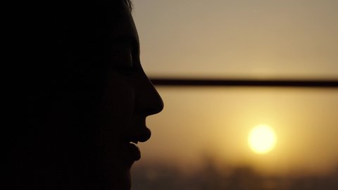 Gestures of happiness and joy, spending quality time with friends, restaurants and cafes in the Kingdom, sipping a favorite drink, a close-up of a veiled Saudi Arabian woman wearing an abaya, sitting in a sophisticated cafe enjoying moments of peace and relaxation, sunset, photographed in the shade