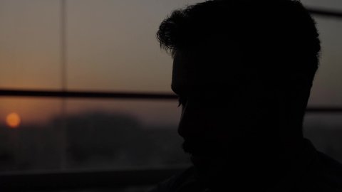 في وقت الغروب تصوير في الظل، العمل في احدى كافيهات ومطاعم، دمج العمل مع التقنية والتكنولوجيا، أجواء الهدوء والاسترخاء داخل كافيه راقي، تصوير مقرب لرجل خليجي عربي سعودي يرتدي الزي الكاجوال يجلس على الكرسي يحمل كأس من المشروبات الباردة، قضاء أوقات ممتعة في الويكند