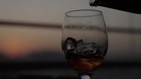 Pour a soft drink into the glass, a close-up shot of a glass filled with ice cubes, a slice of lemon, soft drinks, a refreshing summer drink, cold beverages, enjoying soft drinks with fast food.
