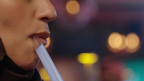 تدخين الشيشة وتناول المشروبات الصيفية الباردة ،في عطلة نهاية الاسبوع قضاء أوقات ممتعه في الخارج، تبادل الاحاديث و الدردشة مع احد الاصدقاء، تصوير مقرب لإمرأة عربية خليجية سعودية ترتدي الحجاب والعباءة تقوم بتدخين الشيشة في إحدى الكافيهات, جلسة وناسة ونقاشات وحوارات