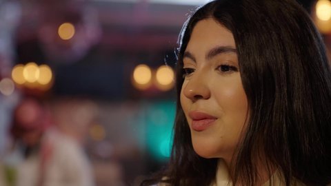 جلسة وناسة وتعارف مع الاصدقاء، قضاء الأوقات الممتعة في الخارج، الاستمتاع بالمشروبات الباردة في فصل الصيف, الاستمتاع بالأنشطة الترفيهية, تصوير مقرب لامرأة عربية خليجية سعودية تجلس في كافي شوب راقي تقوم بشرب كوب من العصير، إيماءات السعادة و السرور