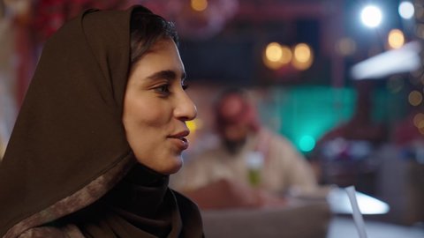 تناول المشروبات الصيفية الباردة وتدخين الشيشة،في عطلة نهاية الاسبوع قضاء أوقات ممتعه في الخارج، تبادل الاحاديث و الدردشة مع احد الاصدقاء، تصوير مقرب لإمرأة عربية خليجية سعودية ترتدي الحجاب والعباءة تقومبشرب العصير في إحدى الكافيهات, جلسة وناسة ونقاشات وحوارات