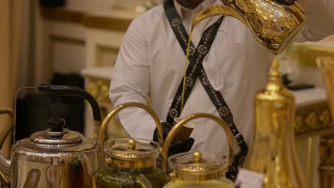التقاليد السعودية الاصيله ، مقدم ضيافة يرتدي الزي التقليدي يقوم بسكب القهوه العربيه الاصيله من دله ذهبية اللون فى احدي قاعات الزفاف فى الدمام بالمملكة العربية السعودية، الضيافة السعودية التقليديه