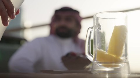 شاب سعودي يسكب العصير، الترويح عن النفسة برفقة الأصدقاء، الاستمتاع بتناول المشروبات ، تصوير مقرب لرجل عربي خليجي سعودي يرتدي الثوب و الشماغ يجلس فى المقهي برفقة صديقة، ايماءات السعادة و السرور، التسامر والضحك بين الأصدقاء، جلسة وناسة ونقاشات وحوارات