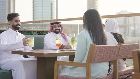 جلسة وناسة ونقاشات وحوارات، الترويح عن النفسة برفقة الأصدقاء، الاستمتاع بتناول المشروبات ، تصوير مقرب لرجل عربي خليجي سعودي يرتدي الثوب و الشماغ يجلس فى المقهي برفقة أصدقائه، ايماءات السعادة و السرور، التسامر والضحك بين الأصدقاء