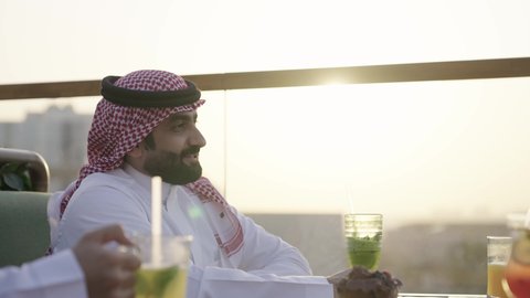 التنزه في وقت العطلة ، صداقات و تعارف ، وصول احدى الصديقات التحية والسلام، التسامر والضحك بين الأصدقاء، جلسة وناسة ونقاشات وحوارات، الترويح عن النفسة برفقة الأصدقاء، تصوير مقرب لرجل عربي خليجي سعودي يرتدي الثوب و الشماغ يجلس فى المقهي برفقة أصدقائه