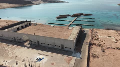 The place where ships dock and stop at the port, the calmness and beauty of the sea, the waterfront in Tabuk, the beach of Haql Governorate on the shores of the Red Sea in Tabuk, Saudi Arabia, drone photography of Haql Marina during its construction, Tabuk's tourist attractions, tourist places, the background of marine nature.