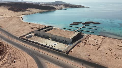 Tourist attractions in Tabuk, a place for ships to dock and stop at the port, the tranquility and beauty of the sea, the waterfront in Tabuk, the beach of Haql Governorate on the shores of the Red Sea in Tabuk, Saudi Arabia, drone photography of Haql Marina during its construction, tourist spots, marine nature background.