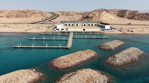 Tourism and natural landscapes, tourist attractions in Tabuk, a place for ships to dock and stop at the port, the tranquility and beauty of the sea, the waterfront in Tabuk, the beach of Haql Governorate on the shores of the Red Sea in Tabuk, Saudi Arabia, drone photography of Haql Marina during its construction, marine nature background.