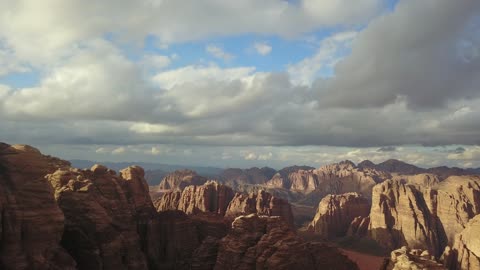 منظر السماء المليء بالغيوم، سلسلة الجبال في منطقة علقان في النهار، معالم حضارية سياحية في المملكة العربية السعودية، جبال منحوتة وتشكيلات جبلية في مدينة تبوك،  تصوير درون جوي للتكوينات الصخرية في قرية بجدة نيوم غرب المملكة العربية السعودية، مناظر طبيعية للرمال الذهبية