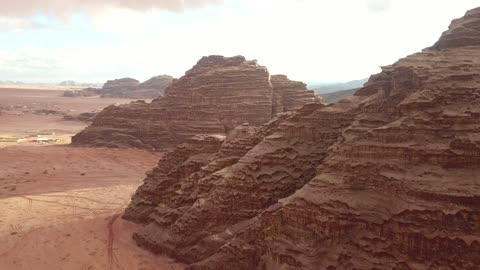 جبال منحوتة وتشكيلات جبلية في مدينة تبوك، معالم حضارية سياحية في المملكة العربية السعودية، سلسلة الجبال في منطقة علقان في النهار، تصوير درون جوي للتكوينات الصخرية في قرية بجدة نيوم غرب المملكة العربية السعودية، مناظر طبيعية للرمال الذهبية