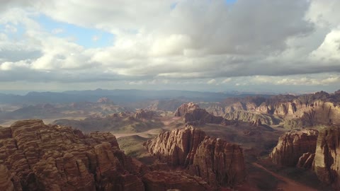 The view of the sky filled with clouds, the mountain range in the Alaqan area during the day, tourist cultural landmarks in the Kingdom of Saudi Arabia, sculpted mountains and geological formations in the city of Tabuk, aerial drone photography of rock formations in the village of Jeddah Neom in the west of the Kingdom of Saudi Arabia, natural landscapes of golden sands.
