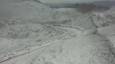 أجواء ثلجية باردة، تساقط الثلوج، أجواء شتوية، معالم حضارية سياحية في المملكة العربية السعودية، سلسلة جبال اللوز في منطقة تروجينا تكسوها الثلوج، تصوير درون جوي للتكوينات الصخرية في قرية بجدة نيوم غرب المملكة العربية السعودية، جبال منحوتة وتشكيلات جبلية في مدينة تبوك