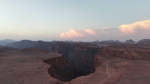 A deep gorge in the ground, a protected desert wilderness area, drone photography of the Shaqri Mountains in Tabuk, Saudi Arabia, mountain formations, Shaqri Rift, mountains and highlands, desert terrain, mountainous nature, mountain fault, natural landmarks of Tabuk.