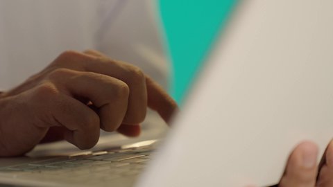 مهن ووظائف ادارية مكتبية, إدارة شؤون الأعمال وتنظيمها عبر الاجهزة التقنية، ايماءات السعادة والسرور بتحقيق الأهداف،  دمج العمل مع التقنية والتكنولوجيا، تصوير مقرب لرجل عربي خليجي عماني يرتدي الدشداشة والكمة  يحمل بيده جهاز الحاسوب المحمول ، خلفية زرقاء