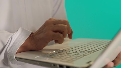 Managing and organizing business affairs through technical devices, gestures of happiness and joy in achieving goals, integrating work with technology and technology, administrative and office job professions, a photo of an Arab Gulf Omani man wearing a dishdasha and kumma holding a laptop in his hand, blue background.