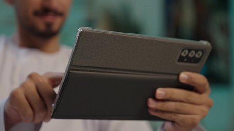 تصفح الانترنت ومواقع التواصل الاجتماعي، انجاز مهام العمل عن بعد، الدردشة والتواصل مع الاصدقاء، اجراء مكالمة الفيديو باستخدام جهاز تقني حديث، رجل عربي خليجي عماني مبتسم يرتدي الكمة والدشداشة يستخدم جهاز التابلت، مفهوم ممارسه الانشطه والعمل عن بعد