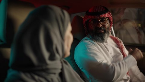 ارتداء حزام الامان ، تقوية الروابط الزوجية والعائلية، تعابير السعادة و السرور، رجل عربي خليجي سعودي يرتدي الثوب الابيض و الشماغ يجلس فى السيارة برفقة زوجته، قضاء وقت ممتع فى الخارج