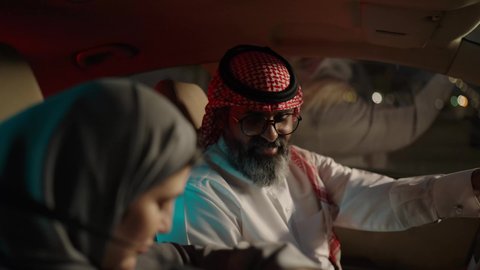 تقوية الروابط الزوجية والعائلية، تعابير السعادة و السرور، رجل عربي خليجي سعودي يرتدي الثوب الابيض و الشماغ يجلس فى السيارة برفقة زوجته، قضاء وقت ممتع فى الخارج