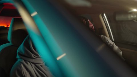 Chat and conversations on the road, a group trip in the car, a Saudi Arabian couple wearing traditional attire sitting on a car trip, enjoying a stroll through the streets of Saudi Arabia, browsing social media on their mobile phone, having a good time outdoors, gestures of happiness and joy.