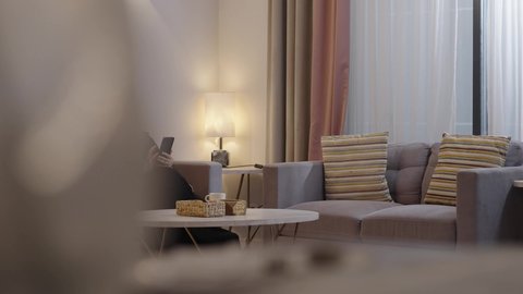 الاستفادة من الجهاز التكنولوجي الحديث في وقت الفراغ، امراة عربية خليجية سعودية محجبة ترتدي العباءة تجلس فى غرفه المعيشة وتمسك بيدها الهاتف المحمول، استخدام الجوال في الدردشة والتواصل مع الأهل و الأصدقاء