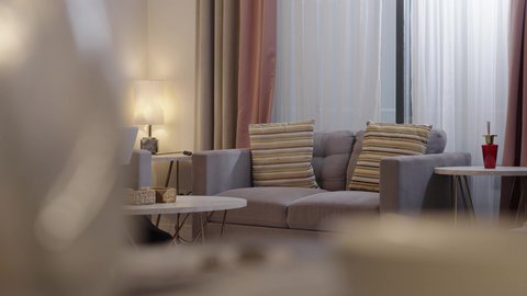 Sipping her favorite drink, using a modern and advanced technological device, a Saudi Arabian Gulf woman in a hijab wearing an abaya sits in the living room using a laptop, watching a movie on the laptop.