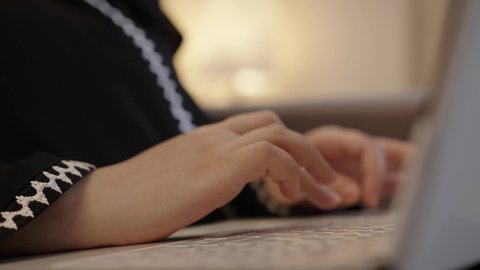 Data entry and typing through the keyboard, integrating work with technology and tech, possessing the skill of fast typing on the keyboard, a close-up shot of the hands of an Arab Gulf Saudi woman wearing an abaya working on a laptop, tasks of administrative office jobs.