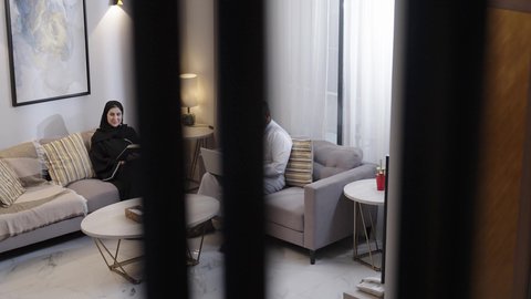 الاهتمام و الرعاية بالابن ، تمضية وقت الفراغ بالتعلم والتثقف الذاتي، رجل عربي خليجي سعودي يرتدي الثوب الابيض يجلس برفقة زوجته و ابنه يعمل على الحاسب المحمول، قضاء وقت عائلى ممتع