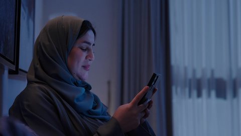 Gestures of joy and happiness, chatting with family and friends, using advanced modern technology and techniques, a close-up shot of a veiled Saudi Arabian Gulf woman looking at her phone, replying to text messages, using modern technologies and devices.