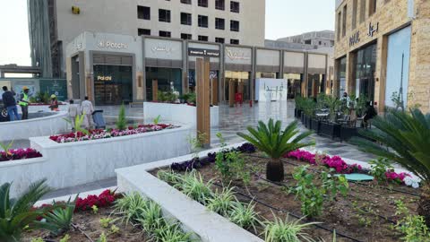 المطاعم والمقاهي والمراكز التجارية المميزة، تصوير درون لمجمع ساس بوليفارد في حي المروج بمدينة تبوك في وقت النهار، وجهة ترفيهية وتجارية حديثة، الفن الهندسي المعماري على الطراز الحديث والمتطور لمشروع جوهرة ساس في المملكة العربية السعودية